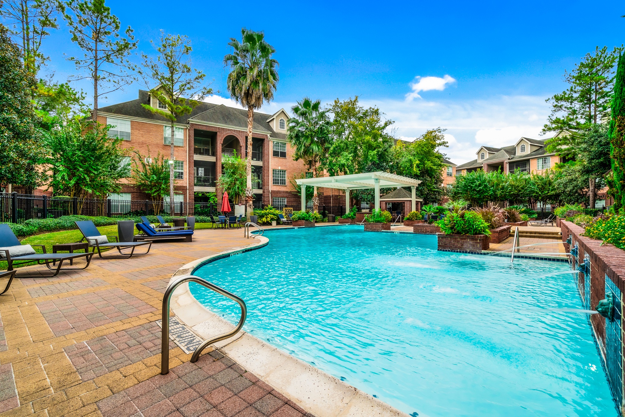 A swimming pool surrounded by a brick patio and a building in the background.